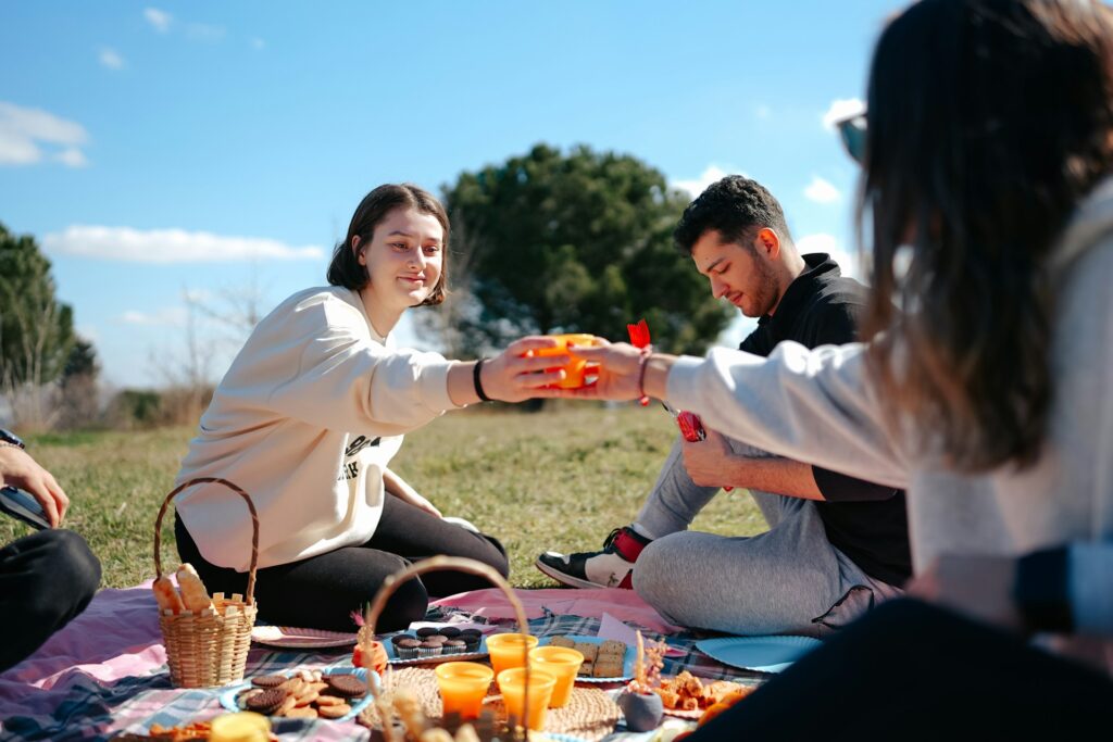 A small group of friends hanging out outside eating a picnic